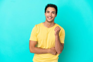 Kafkasyalı yakışıklı adam soyutlanmış mavi arka planda gülüyor.