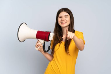 Beyaz arka planda izole edilmiş genç Ukraynalı bir kız elinde bir megafon, elinde gülümseyerek ön tarafı işaret ediyor.