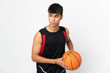 İzole edilmiş beyaz arka planda basketbol oynayan genç bir adam.