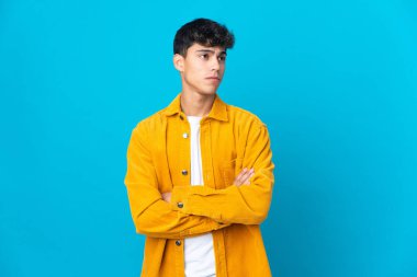 Genç adam soyutlanmış mavi arka plan yan tarafa bakıyor.