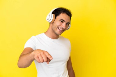 Kafkas yakışıklı adam izole edilmiş sarı arka planda müzik dinliyor.