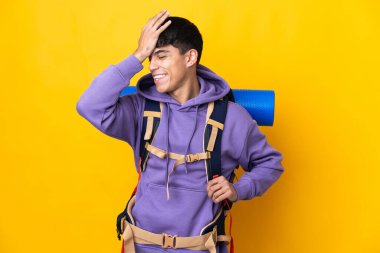 Sarı arka plan üzerinde büyük bir sırt çantası olan genç dağcı bir şey fark etti ve çözüme niyetlendi.