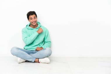 Beyaz tenli yakışıklı adam yerde oturmuş zaferi kutluyor.