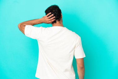 Kafkasyalı yakışıklı adam arka planda soyutlanmış mavi arka planda ve düşünüyor