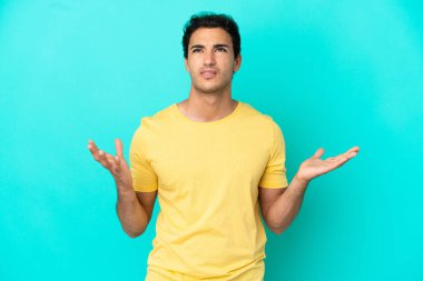 İzole edilmiş mavi arka planda beyaz, yakışıklı bir adam stresli.