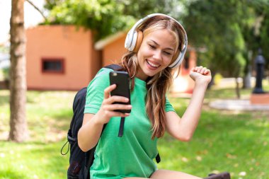 Dışarıda cep telefonu kullanan genç bir bayan öğrenci.