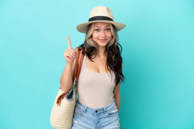 Pamel ve plaj çantalı genç Rus kız mavi arka planda izole edilmiş işaret parmağıyla işaret etmek harika bir fikir.