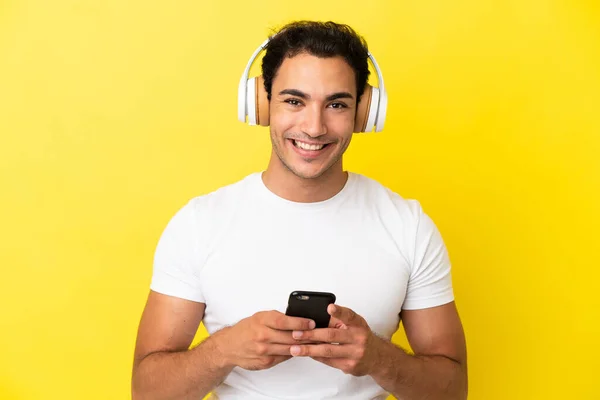 Καυκάσιος Όμορφος Άντρας Πάνω Από Απομονωμένο Κίτρινο Φόντο Ακούγοντας Μουσική — Φωτογραφία Αρχείου