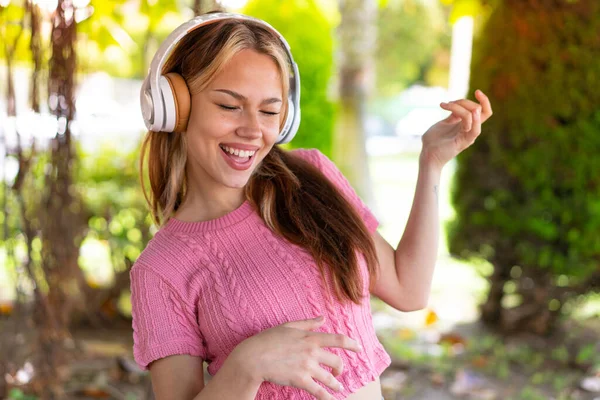 Mladá Hezká Žena Venku Poslouchá Hudbu Dělá Kytarové Gesto — Stock fotografie