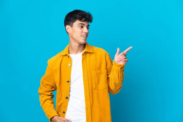 Junger Mann Über Isoliertem Blauem Hintergrund Zeigt Mit Dem Finger — Stockfoto
