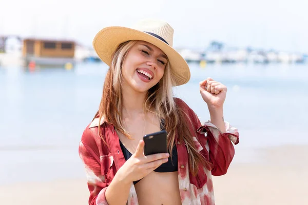 Молодая Красивая Женщина Летние Каникулы Пляже Телефоном Победной Позиции — стоковое фото