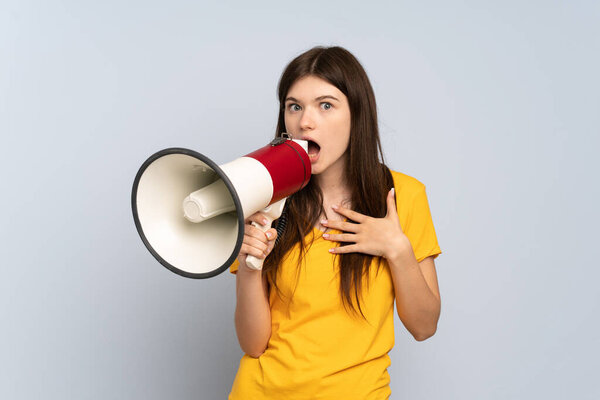 Young Ukrainian girl isolated on white background shouting through a megaphone with surprised expression