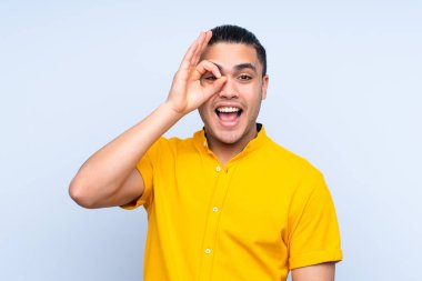 Asyalı yakışıklı adam izole edilmiş arka planda parmaklarıyla işaret veriyor.