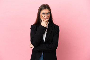 Genç beyaz kadın pembe arka planda soyutlanmış düşünüyor.