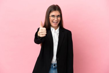 Genç beyaz kadın pembe arka planda izole edildi. Başparmakları havada çünkü iyi bir şey oldu.