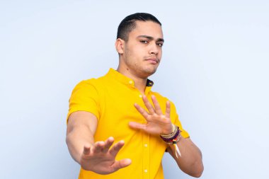 Asyalı yakışıklı adam soyutlanmış arka planda gergin ellerini öne uzatıyor.