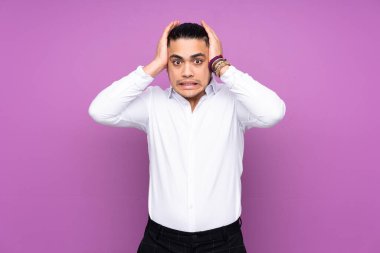 Asyalı yakışıklı adam mavi arka planda izole edilmiş, gergin hareketler yapıyor.