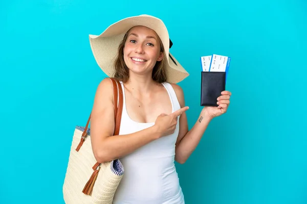 青い背景に隔離されたパネルとビーチバッグとパスポートを保持し それを指す若い白人女性 — ストック写真