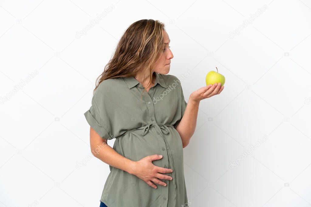 Young caucasian woman isolated on white background pregnant and holding an apple