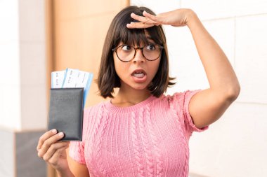 Şehirdeki genç esmer kadın uzakta bir yere bakarken pasaportu ve uçak biletleriyle geziyor.