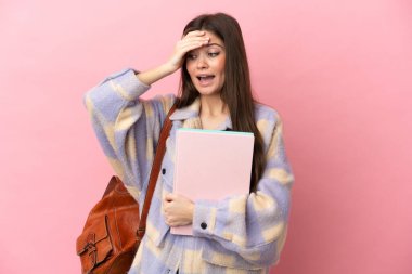 Pembe arka planda izole edilmiş genç bir bayan yan tarafa bakarken sürpriz jest yapıyor.