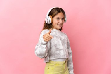 İzole edilmiş pembe arka planda müzik dinleyen çocuk