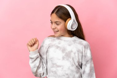 İzole edilmiş pembe arka plan müzik ve dans dinleyen çocuk.