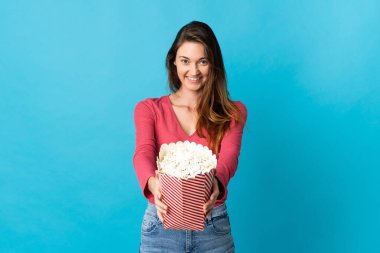 Genç İrlandalı bir kadın mavi arka planda izole edilmiş elinde koca bir kova patlamış mısır tutuyordu.