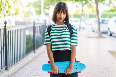 Açık havada patenli esmer bir kadın.