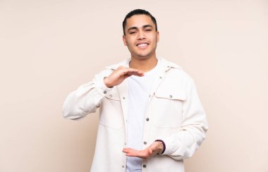 Asyalı yakışıklı, izole edilmiş arka plan üzerinde. Avucunun içine reklam koymak için hayali bir alan tutuyor.