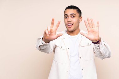 Asyalı yakışıklı adam tecrit edilmiş arka planda sekiz parmağıyla sayıyor.