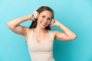 Genç beyaz kadın mavi arka planda izole edilmiş müzik dinliyor.