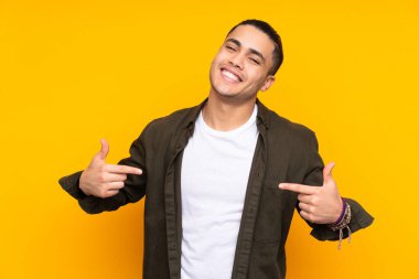 Asyalı yakışıklı adam sarı arka planda izole edilmiş bir fikir düşünüyor.