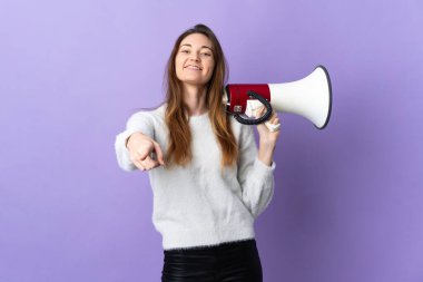 Mor arka planda izole edilmiş genç bir İrlandalı kadın elinde bir megafon ve ön tarafı göstererek gülümsüyor.
