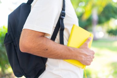 Dışarıda elinde bir defter tutan genç bir öğrenci.