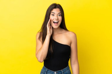 Sarı arka planda izole edilmiş genç Brezilyalı kadın şaşırmış ve şok olmuş bir yüz ifadesi var.