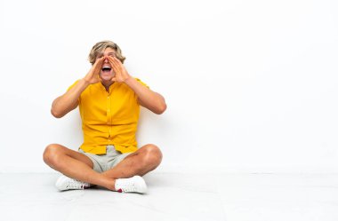 Genç İngiliz adam yerde oturmuş bağırıyor ve bir şeyler söylüyor.