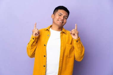 Genç Ekvadorlu adam mor arka planda izole edilmiş. Harika bir fikre işaret ediyor.