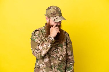 Sarı arka planda izole edilmiş asker kızıl saçlı adam gülüyor.