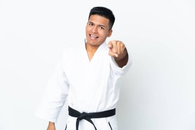 Young Ecuadorian man doing karate isolated on white background surprised and pointing front