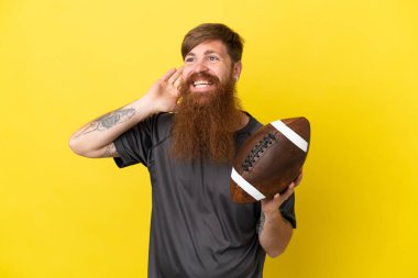 Kızıl saçlı beyaz adam sarı arka planda ragbi oynuyor. 