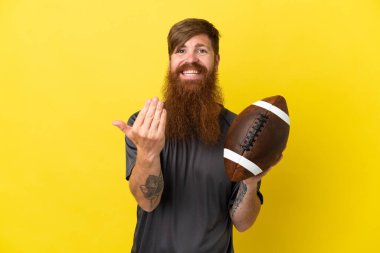 Kızıl saçlı beyaz adam sarı arka planda ragbi oynuyor. 