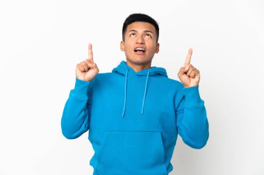 Young Ecuadorian man isolated on white background surprised and pointing up