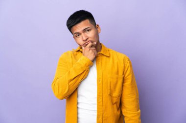 Genç Ekvadorlu adam, mor arka planda izole edilmiş. Şüpheleri var.