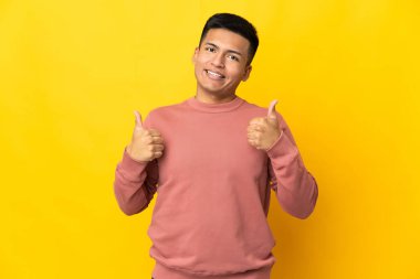 Young Ecuadorian man isolated on yellow background giving a thumbs up gesture