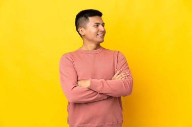 Genç Ekvadorlu adam sarı arka planda izole edilmiş mutlu ve gülümsüyor.