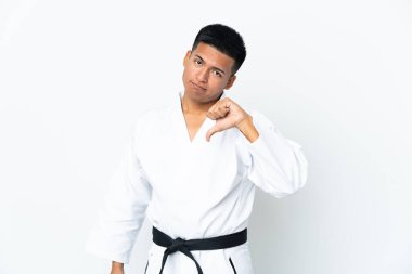 Young Ecuadorian man doing karate isolated on white background showing thumb down with negative expression