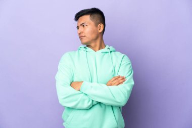 Young Ecuadorian man isolated on purple background looking to the side