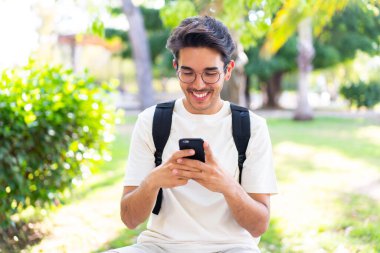 Dışarıda cep telefonu kullanan genç bir öğrenci.