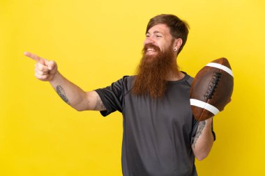 Kızıl saçlı beyaz adam sarı arka planda ragbi oynuyor. 